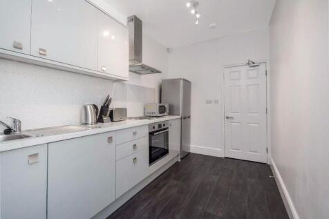 Bright modern galley kitchen with white cabinet...