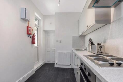 Bright, modern galley kitchen with white cabine...