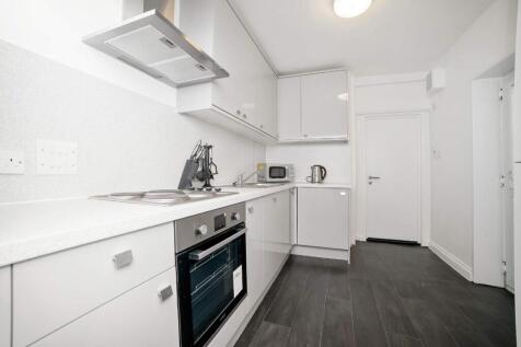 Bright modern galley kitchen with integrated ov...