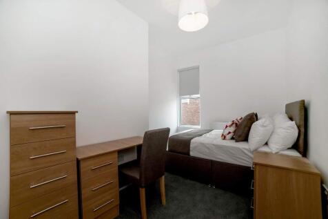 Bright, neatly furnished bedroom with a comfort...