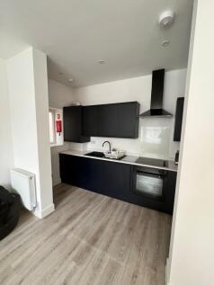 Sleek modern kitchenette with dark cabinets, in...