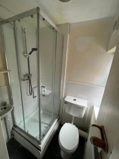 Compact bathroom featuring a modern shower encl...