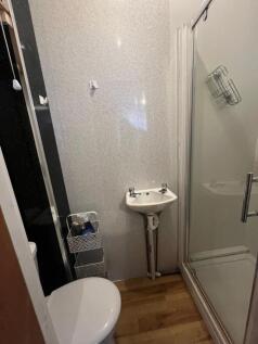 Compact bathroom featuring a shower enclosure, ...
