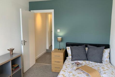 Bright, neatly arranged single bedroom with a f...