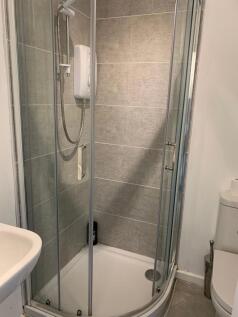 Modern tiled bathroom with a curved glass showe...