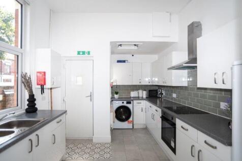 Bright, modern galley kitchen with white fitted...