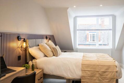 A bright, modern bedroom featuring a neatly mad...