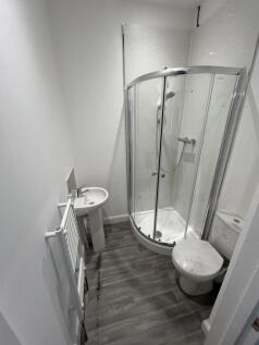 Bright, modern bathroom with a curved glass sho...