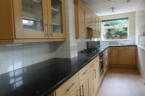 Bright galley kitchen with a long black granite...