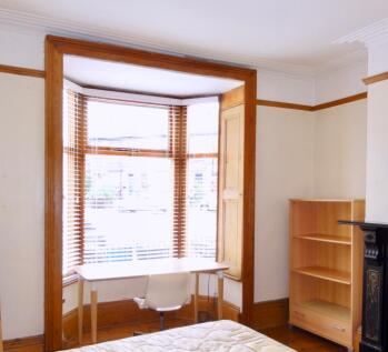 Bright bedroom with a large bay window and wood...