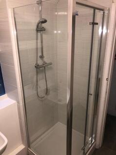 Bright, modern tiled shower enclosure with a ch...