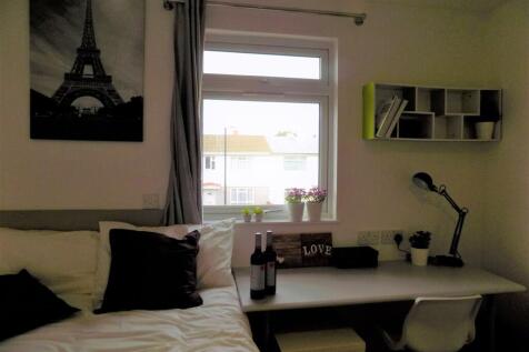 Bright, neatly styled bedroom with a desk by th...