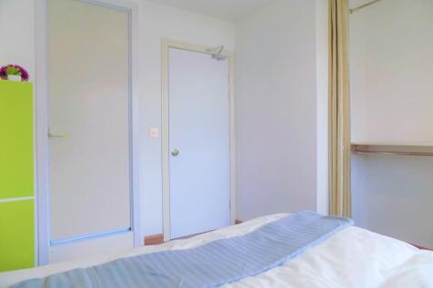 Bright, tidy bedroom with fresh white walls, a ...