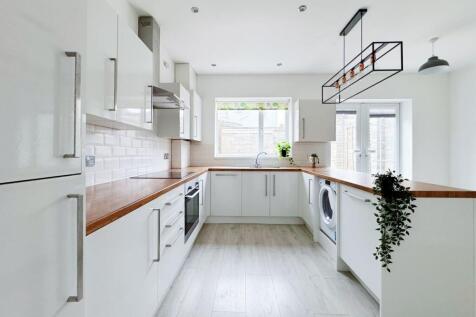 Bright, modern galley kitchen with white cabine...