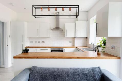 Bright modern kitchen with white cabinetry, woo...
