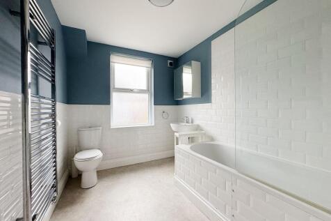 Bright, modern bathroom with a white tile-lined...