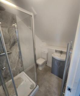 Modern compact bathroom with a corner shower en...