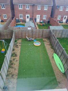 Long fenced rear garden with artificial lawn, g...