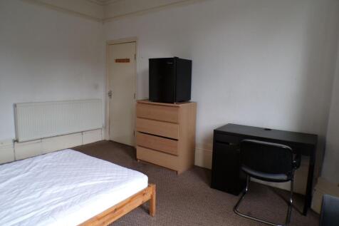 Bright simple bedroom with a wooden bed frame a...