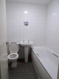 Compact all-white bathroom with a bath, pedesta...
