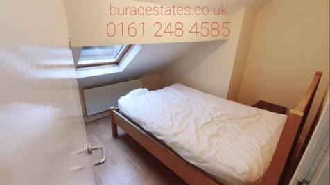 A cozy single bedroom featuring a simple wooden...