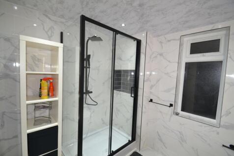 Modern tiled bathroom with a large framed glass...