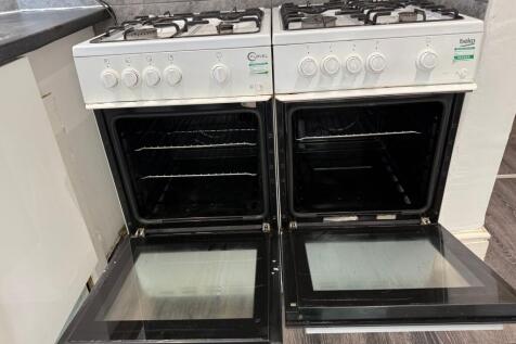 Twin gas cookers with open oven doors set into ...