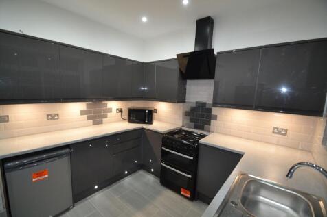 Modern kitchen featuring sleek dark cabinetry, ...