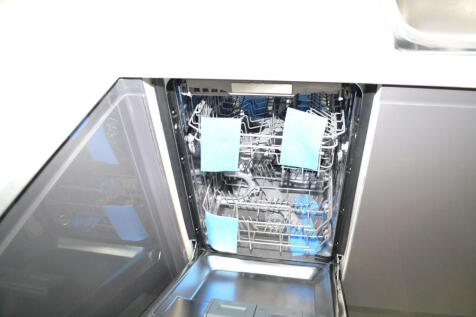 Open stainless-steel dishwasher with pull-out r...