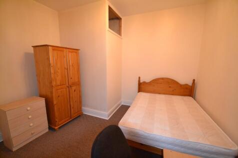 A cozy student bedroom featuring a wooden bed f...