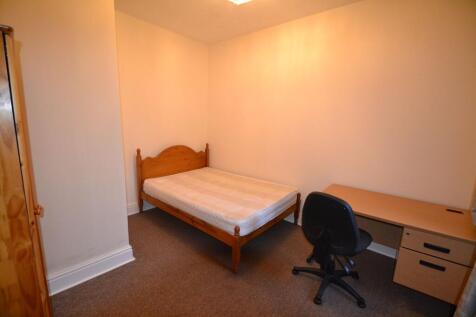 A cozy single bedroom featuring a wooden bed fr...