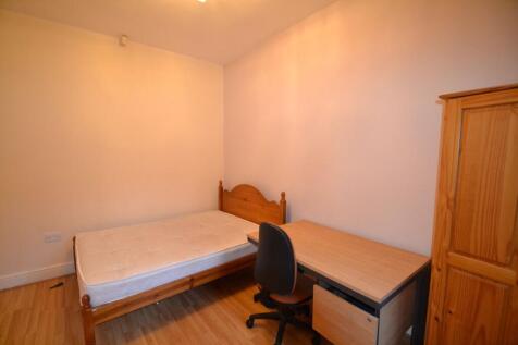 A cozy single bedroom featuring a wooden bed fr...