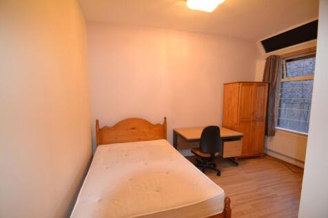 A cozy single bedroom featuring a wooden bed fr...