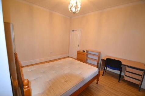 A cozy single bedroom featuring a wooden bed fr...