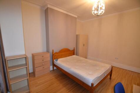 A cozy double bedroom featuring a wooden bed fr...