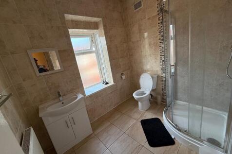 Bright, modern tiled bathroom with a curved gla...