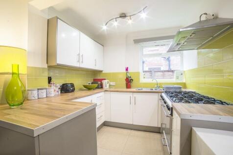 Modern galley kitchen with white cabinets, ligh...