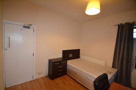 A cozy single bedroom featuring a simple bed an...