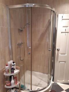 Modern tiled bathroom with a curved glass showe...