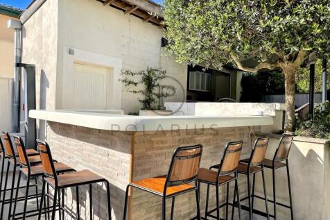 Outdoor bar area with high stools, under a tree, n