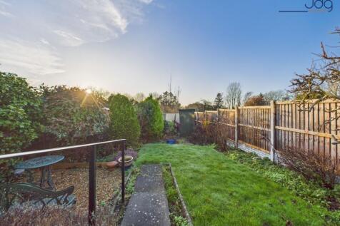 A generous, tiered rear garden with paved seating areas and lawn