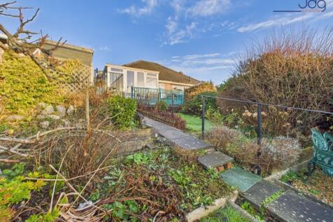 A generous, tiered rear garden with paved seating areas and lawn