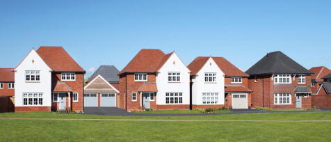 Row of modern detached houses with brick and white exteriors, pitched roofs, and front gardens under