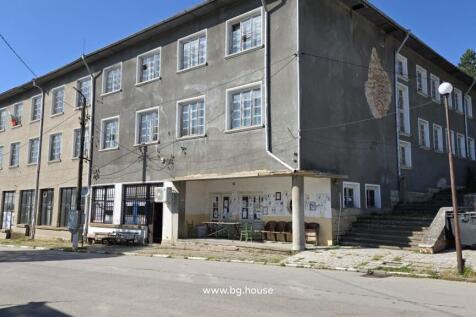 Front and side view of a three-storey commercial building with a covered porch and multiple windows in village Goritsa