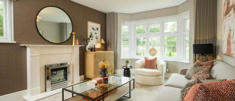 Interior view of a cosy living room with a white fireplace, a large bay window, and stylish furnitur