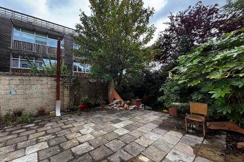 Spacious paved courtyard with lush greenery...