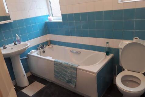 Bright, tiled bathroom featuring a full-size ba...