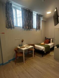 Bright, neatly furnished single bedroom with a ...