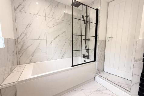 Elegant marble-tiled bathroom with modern bath ...