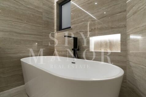 Close-up view of the freestanding bathtub with a black faucet and an illuminated wall niche in the Carvoeiro villa's modern bathroom.